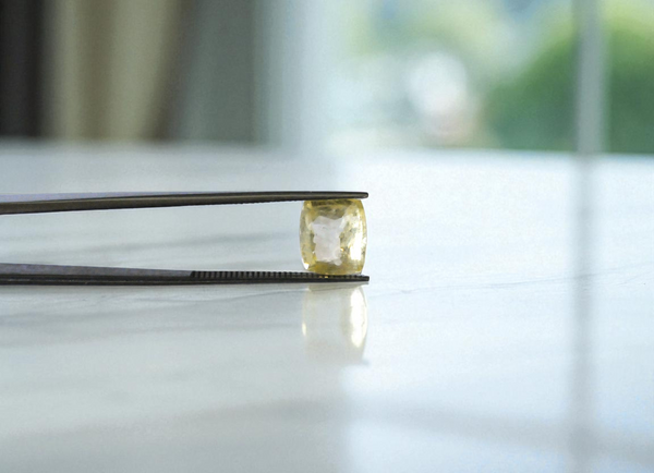 Ceylon yellow sapphire held in tweezers